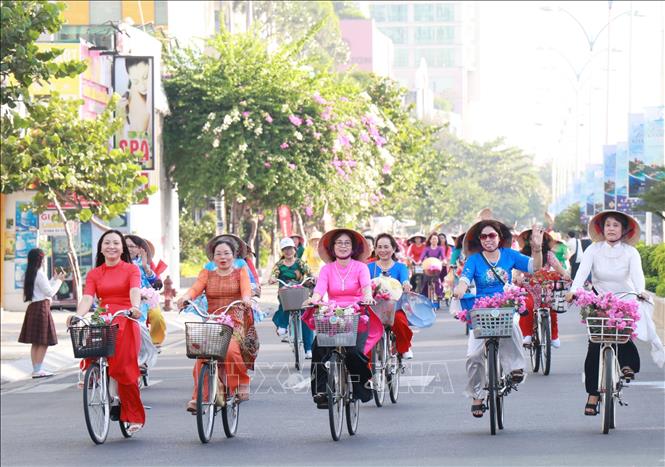 Những chiếc xe đạp chở giỏ hoa cùng tà áo dài tung bay diễu hành trên tuyến đường biển đẹp ở Nha Trang. Ảnh: Phan Sáu - TTXVN