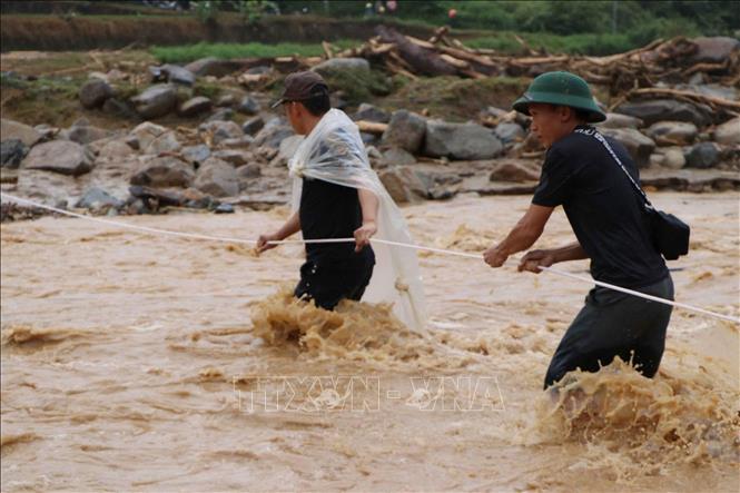 Nước lũ nhiều chỗ vẫn chảy xiết, lực lượng cứu hộ phải căng dây để hỗ trợ người dân di chuyển an toàn. Ảnh: Nguyễn Oanh - TTXVN