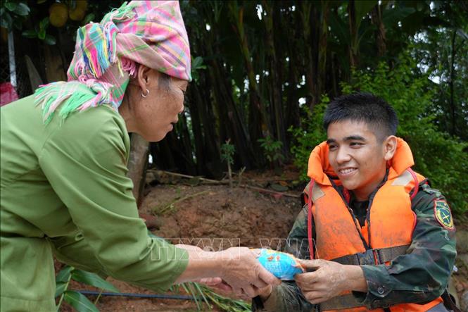 Người dân xã Mường Than chia sẻ đồ ăn, động viên lực lượng cứu hộ. Ảnh: Nguyễn Oanh - TTXVN