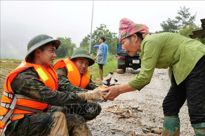Người dân xã Mường Than chia sẻ nước uống cùng lực lượng cứu hộ. Ảnh: Nguyễn Oanh - TTXVN
