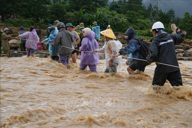 Người dân bám dây qua suối để đi đưa tang người đã mất. Ảnh: Nguyễn Oanh-TTXVN