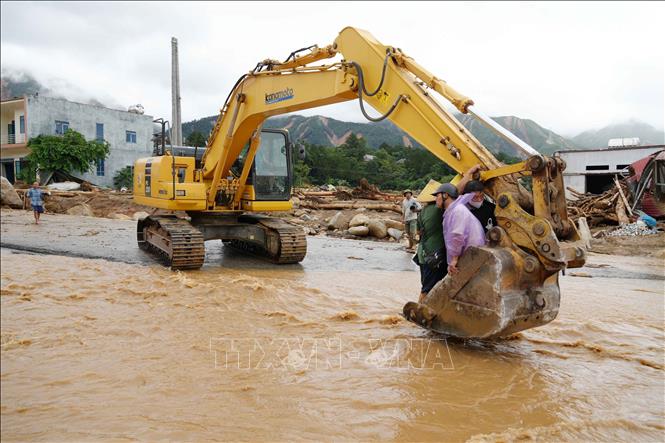 Lũ dần rút, người dân qua suối bằng máy xúc. Ảnh: Nguyễn Oanh - TTXVN