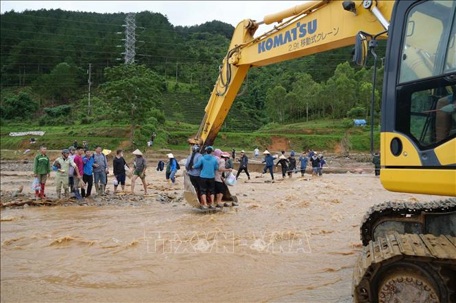 Lũ dần rút, người dân qua suối bằng máy xúc. Ảnh: Nguyễn Oanh - TTXVN