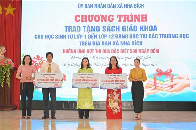 Đại diện lãnh đạo xã Nha Bích trao tặng sách giáo khoa cho các trường học. Ảnh: Đậu Tất Thành - TTXVN
