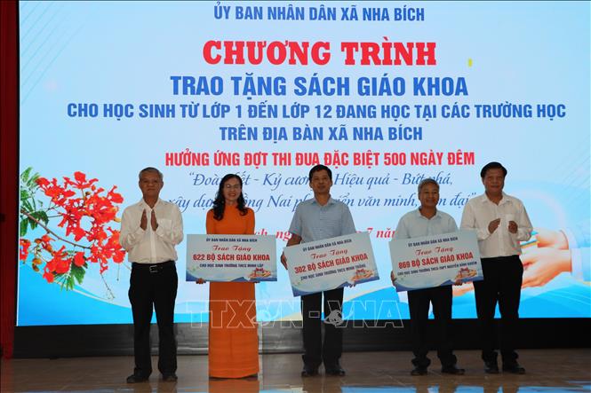 Đại diện lãnh đạo xã Nha Bích trao tặng sách giáo khoa cho các trường học. Ảnh: Đậu Tất Thành - TTXVN