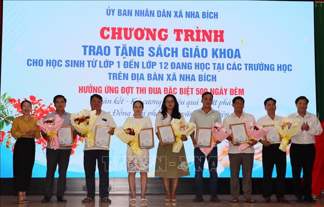 Đại diện lãnh đạo UBND xã Nha Bích tặng hoa cho các đơn vị tài trợ. Ảnh: Đậu Tất Thành - TTXVN