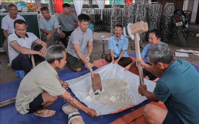 Giã bánh giầy, biểu tượng cho bầu trời từ sự tích Lang Liêu, đòi hỏi sự phối hợp nhịp nhàng, sức mạnh của các thanh niên. Phong tục này không chỉ dâng cúng tổ tiên mà còn khơi dậy tinh thần đoàn kết, lòng biết ơn đất trời. Ảnh: Phan Phương – TTXVN