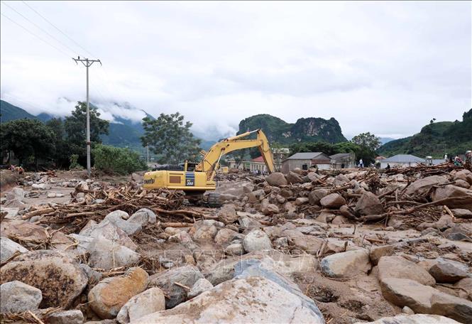 Phương tiện máy móc khơi thông, uốn dòng chảy để nhanh chóng khắc phục giao thông trên tuyến Quốc lộ 32. Ảnh: Quý Trung - TTXVN