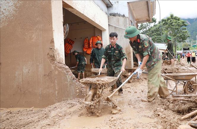 Lực lượng Quân đội giúp dân dọn bùn đất, đá trôi vào nhà tại xã Mường Than. Ảnh: Quý Trung - TTXVN