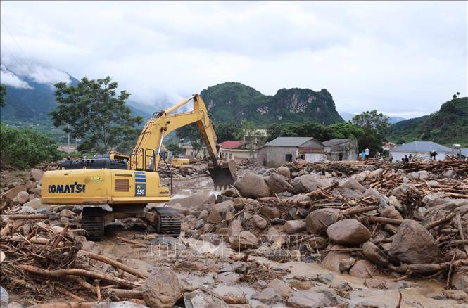 Phương tiện máy móc khơi thông, nắn dòng chảy để nhanh chóng khắc phục giao thông trên tuyến Quốc lộ 32, góp phần ổn định cuộc sống người dân sau lũ. Ảnh: Quý Trung - TTXVN