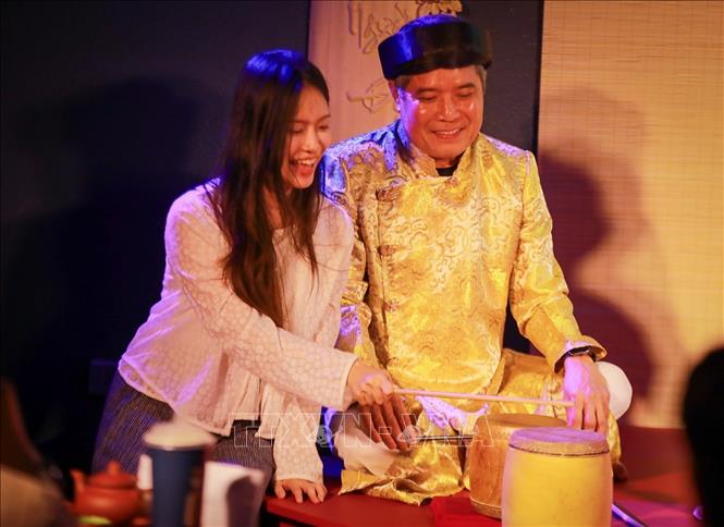 Khán giả trải nghiệm nhạc cụ trống chầu của nghệ thuật hát Ca trù. Ảnh: Khánh Hoà - TTXVN